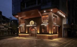 Exterior view of a brown coffee shop at night with a clock on the facade and inviting atmosphere