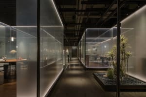 A warm and inviting office hallway with wooden walls, chairs, and potted plants, conveying a sense of organization and functionality