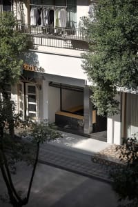 Exterior view of a rustic cafe with a large window, two benches, and a dining table in a relaxed and inviting atmosphere
