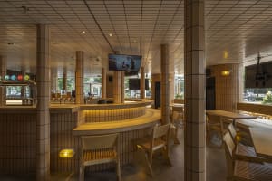 A casual bar area with a counter and three chairs, a TV screen above, and a focus on socializing and enjoying food or drinks