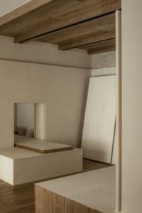 Empty minimalist living space with a white wall, wooden floors, and two mirrors, creating a calm and minimalistic atmosphere