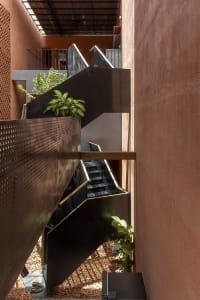 A calm and inviting staircase with wooden steps and a black railing, flanked by two potted plants