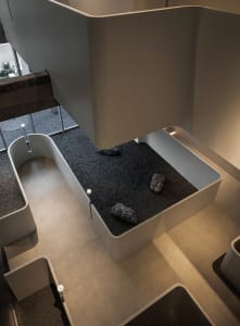Open modern living area with a large white wall, rocks, and a clean minimalistic atmosphere