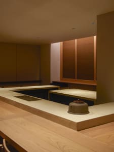 Warm and inviting Asian-style kitchen with wooden walls, stone countertops, and two sinks, set against a neutral background