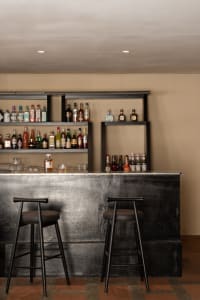Modern bar area with a black countertop, stools, and bottles on display