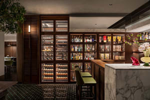 A cozy bar area with a display case of liquor bottles, multiple chairs, and a comfortable seating arrangement