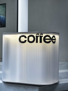A modern coffee shop counter with a sleek stainless steel surface, showcasing the coffee shop's logo in a contemporary and inviting environment