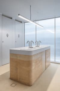 A well-lit bathroom with three toilets and a sink, featuring a clean and functional space for personal hygiene and comfort