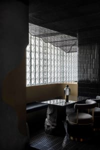 Modern restaurant dining area with black walls, white surfaces, and natural light from glass windows
