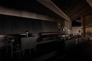 Sophisticated restaurant interior with a black countertop, a couch, and multiple chairs around a dining table