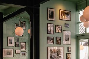 A restaurant wall with a gallery of framed pictures in various sizes, arranged to create a decorative display on a green wall