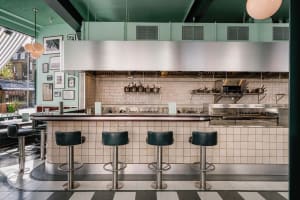 Industrial-style restaurant kitchen with a counter, stools, appliances, and organized storage