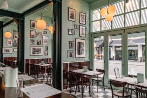 A restaurant interior with green walls, checkered floors, and various seating arrangements, creating a cozy atmosphere for guests