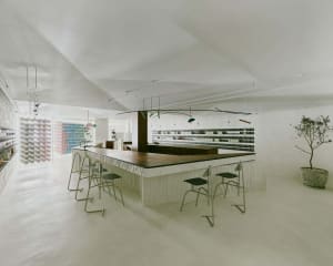 Empty restaurant with a long wooden bar counter, chairs, and a clean, well-organized atmosphere