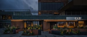 A modern glass building at night with multiple windows and potted plants, featuring a sophisticated and contemporary design