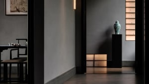 Dimly lit modern hallway with black doorway, two vases on either side, and clean lines