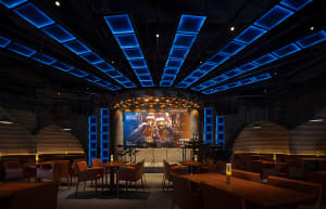 A cozy restaurant bar with wooden accents, chairs, and tables, featuring bottles and a warm atmosphere