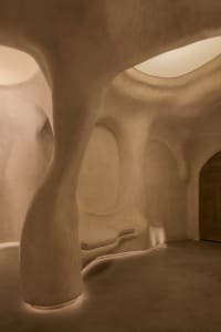 A serene white room with curved walls and a dome ceiling, featuring two benches and a calm atmosphere