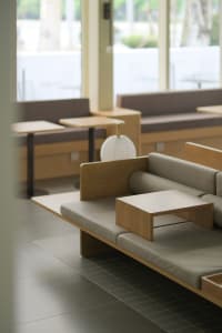 A modern living area with multiple couches and chairs arranged in a comfortable and inviting space, predominantly made of wood, with a warm atmosphere