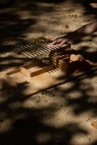 A 3D architectural model of a modern house on display in a sandy area, showcasing its geometric facade and design elements