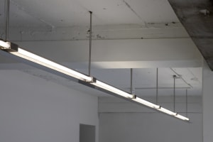 A bright and modern hallway with a long white corridor and lights hanging from the ceiling