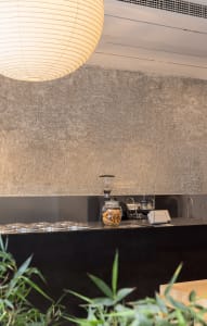 Modern restaurant counter area with a cement wall, display items, vases, and a minimalist atmosphere
