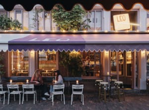 Outdoor dining area with tables and chairs under a large umbrella, featuring a relaxed and inviting atmosphere