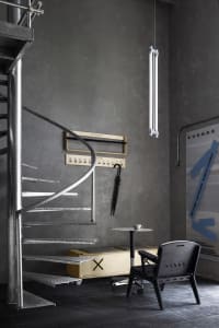 Modern living space with metal staircase, a chair, and a dining table in a contemporary and stylish environment