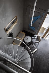 A modern staircase with a metal railing in a residential building, well-lit with possible natural and artificial light sources