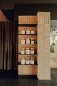 Warm and inviting interior space with a brick wall, wooden shelf, and jars filled with various substances