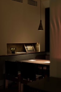 A cozy dining area with a wooden table surrounded by chairs, a book, and a vase, perfect for a meal or conversation