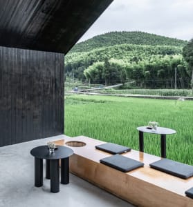 A relaxed outdoor patio area with a wooden table and three black chairs, perfect for casual dining or conversation