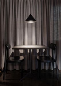 A darkened dining space with a symmetrical arrangement of chairs and a wooden table, creating a cozy and intimate atmosphere