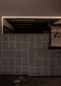 Warm and inviting room with a wooden panelled wall featuring a unique pattern, illuminated by two lights on either side