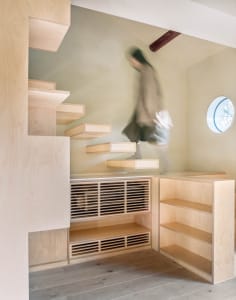 A minimalist interior with a wooden staircase, leading to another level, in a small house