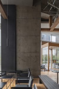 Empty modern restaurant interior with concrete walls and floors, featuring a dining table and chairs in a minimalist setting