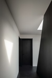 A simple hallway with a black door and a white wall, creating a striking contrast