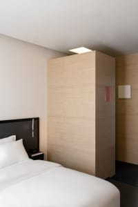 Cozy bedroom with a bed against a wall, nightstands, and a mounted television, creating a comfortable atmosphere