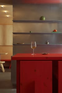 Cozy dining space with a red table, silver walls, and decorative bowls and a wine glass