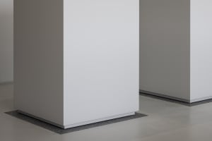 Empty white room with a large concrete wall, minimalist and serene atmosphere