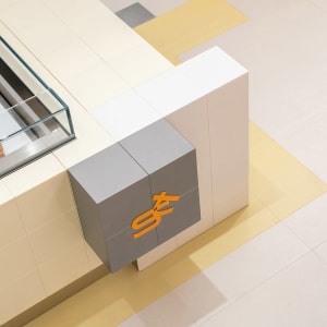 A modern interior design featuring a large white wall with a gray concrete block structure in front of it