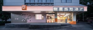 Warm and inviting Asian restaurant with a pink exterior and orange interior, featuring natural light, dining tables, and chairs