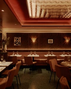 Sophisticated dining space with tables, chairs, wine glasses, artwork, and well-lit spaces