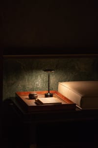 Cozy bedroom with a wooden headboard, a nightstand with two books, and a lamp providing soft lighting