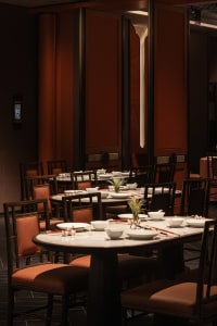 An inviting restaurant with dining tables, chairs, and table settings, creating a warm atmosphere for guests to enjoy meals