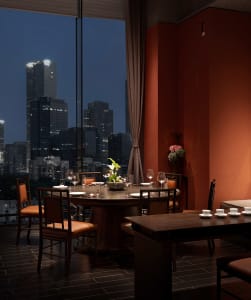 A dining table set with wine glasses and vases in a dimly lit restaurant with red walls and a sophisticated atmosphere