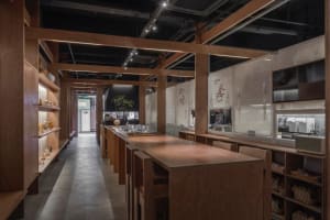 Industrial kitchen with wooden floors and walls, featuring chairs and dining tables, with a clean and organized atmosphere