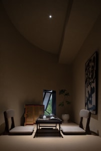 Dimly lit dining room with a table and chairs, adorned with Asian artwork on the walls