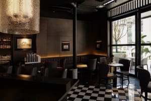 Modern cafe with a black and white checkered tile floor, featuring multiple chairs and dining tables in a stylish atmosphere