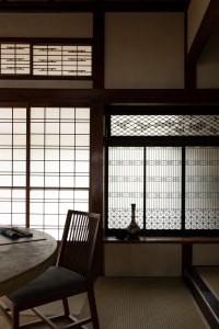 Dining area with a wooden table and modern chairs, surrounded by Asian-style decorations and a cozy atmosphere created by a fireplace